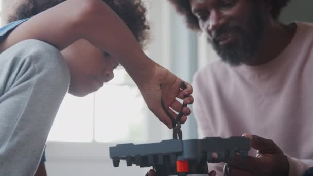 펜치를 사용하여 장난감을 만드는 소년의 클로즈 아버지는 가까이 전경에 초점을 — 비디오