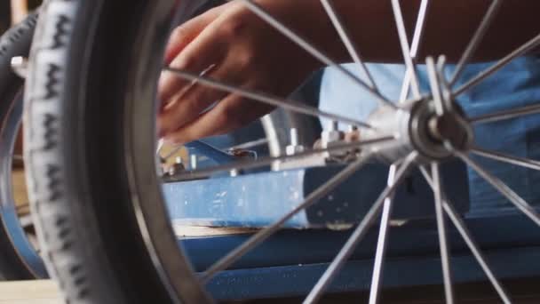 前青少年男孩使用扳手拧紧螺栓上的螺母 将车轮连接到他的赛车卡丁车 中段细节 通过车轮辐条看到 — 图库视频影像