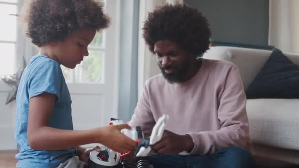 中年黑人父亲在家里帮助他的前十几岁的儿子建造一个机械玩具 侧视图 — 图库视频影像