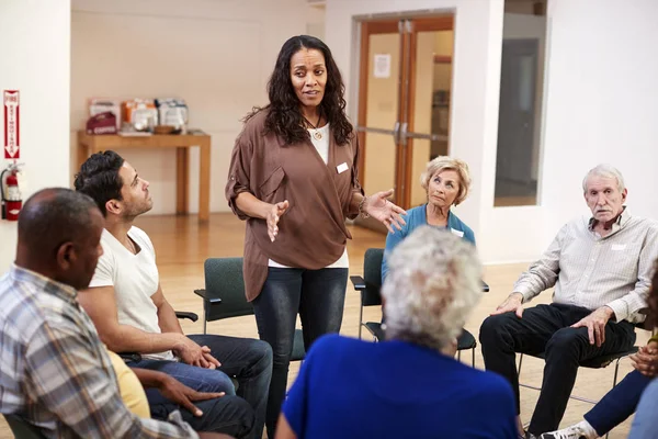 Woman Standing To Address Self Help Therapy Group Meeting In Community Center