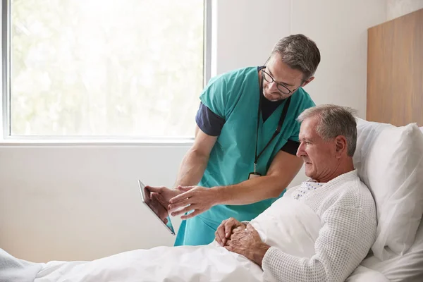 Dijital Tabletli Cerrah Geriatrik Ünitesinde Hastane Yatağında Kıdemli Erkek Hastayı — Stok fotoğraf