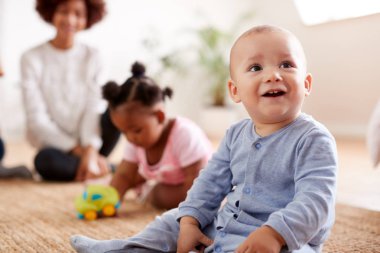 Mother Watching As Playing Babies At Home In Loft Apartment clipart