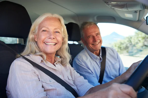 高级白人妇女和她的丈夫开车在他们的车微笑到相机 侧视图 — 图库照片