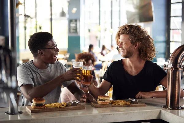 スポーツバーで食べ物を食べ ビールを飲む2人の男性の友人 — ストック写真