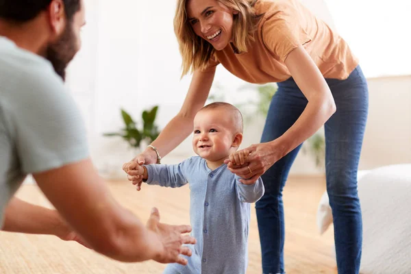 Ouders Thuis Bemoedigende Baby Zoon Nemen Eerste Stappen — Stockfoto