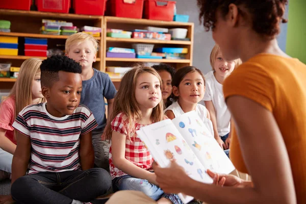 Groep Basisschoolleerlingen Zittend Vloer Luisteren Naar Vrouwelijke Leraar Lezen Verhaal — Stockfoto