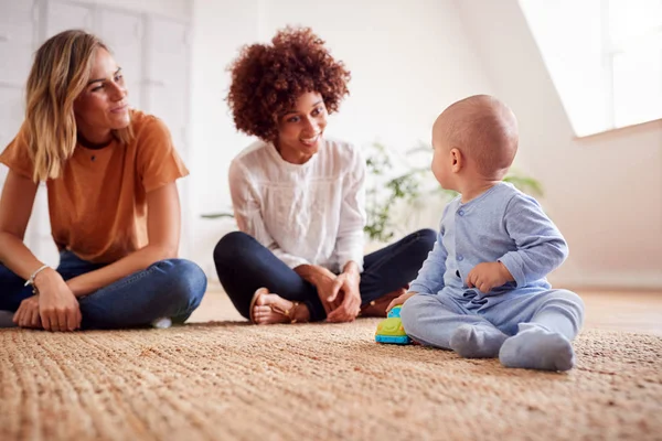 ロフトアパートで自宅で赤ちゃんと遊ぶ女性の友人と母親 — ストック写真