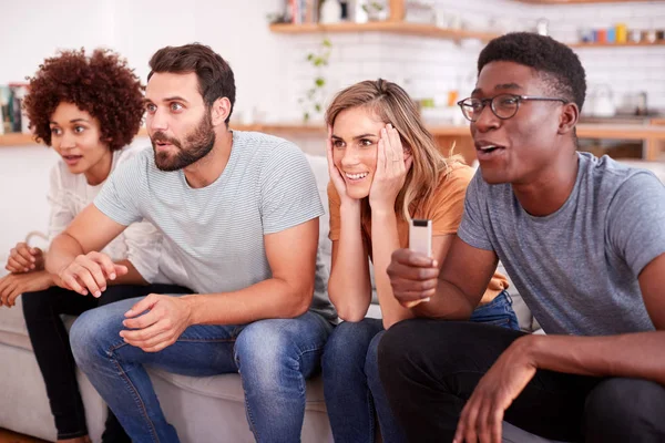 Excited Group Of Friends Sitting On Sofa And Watching Sport On TV