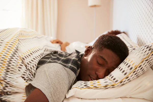 若いアフリカ系アメリカ人男性は 午前中にベッドで眠っている バックグラウンドでパートナーは 前景に焦点を当てます — ストック写真
