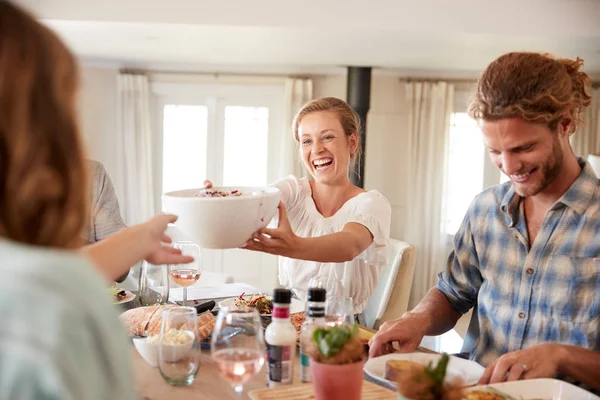 夕食のテーブルで昼食中に食べ物を渡す若い大人の友人 クローズアップ — ストック写真