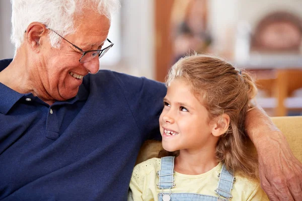 微笑的祖父坐在与孙女在家里的Sofa — 图库照片