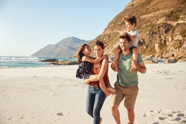 家族の休暇中に子供を運ぶビーチで一緒に歩く中間大人の白いカップル — ストック写真