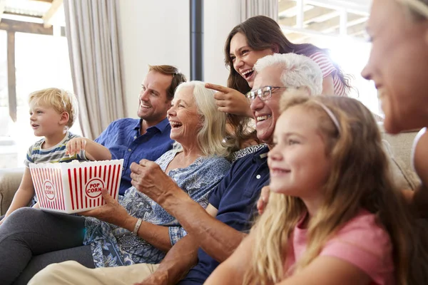 自宅でソファに座ってポップコーンを食べ 一緒に映画を見ている多世代の家族 — ストック写真