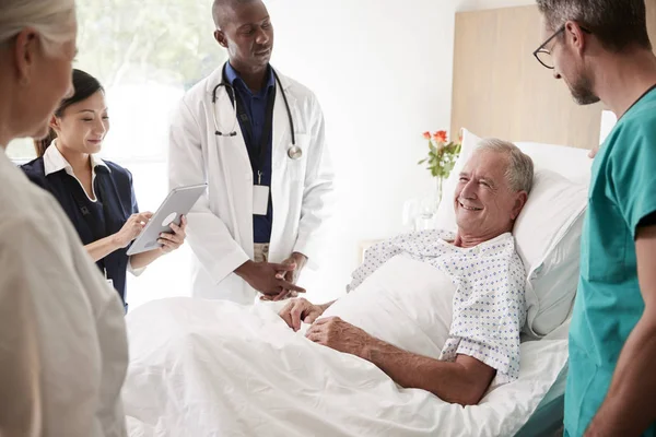 医疗队在老年男性病人病床周围举行轮次会议 — 图库照片