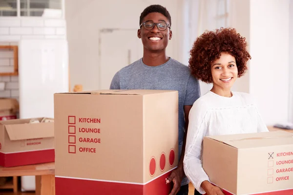 引っ越しの日に新しい家に箱を運ぶ笑顔のカップルの肖像 — ストック写真