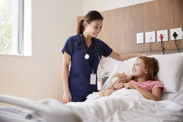Vrouwelijke Verpleegster Een Bezoek Aan Meisje Liggend Ziekenhuis Bed Knuffelen — Stockfoto