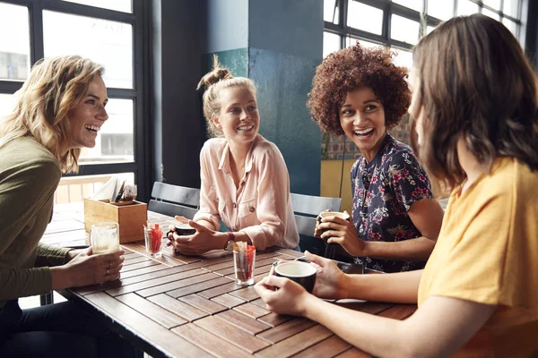 4人の若い女性の友人が喫茶店のテーブルに座って話をする — ストック写真