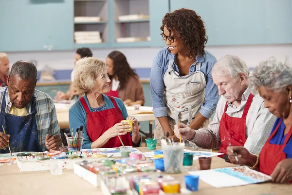 Group Of Retired Seniors Attending Art Class In Community Centre With Teacher