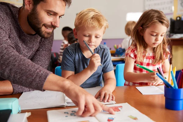 Grundskola Lärare Hjälpa Eleverna När Arbetar Vid Skrivbordet Classroom — Stockfoto