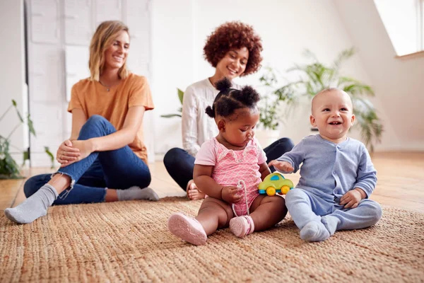 ロフトアパートの自宅で赤ちゃんと遊ぶ2人の母親の会合 — ストック写真