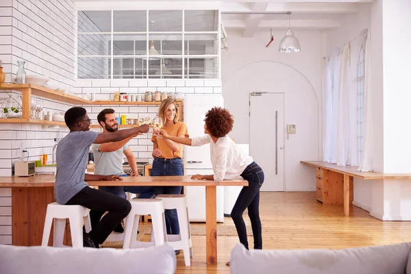 Two Couples Relaxing In Kitchen At Home Making A Toast With Glasses Of Wine Together