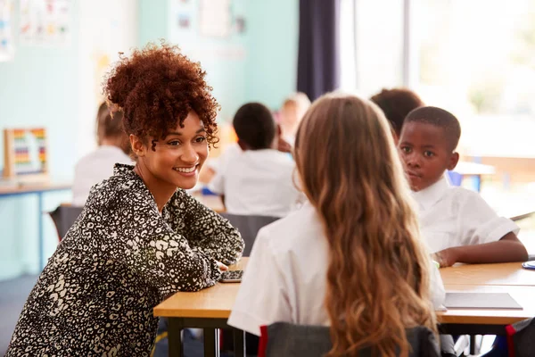 Professora Escola Primária Ajudando Alunos Usar Uniforme Como Trabalham Mesa — Fotografia de Stock