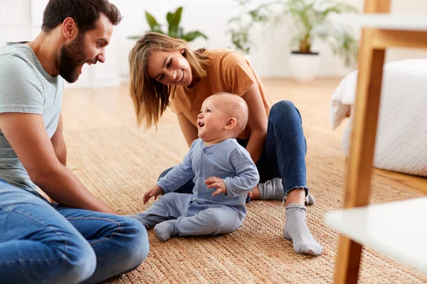 赤ちゃんの息子と遊んで家で床に座っている両親 — ストック写真