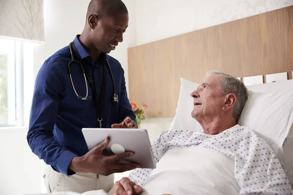 医生与数字平板电脑访问和与老年男性患者在医院病床上交谈 — 图库照片