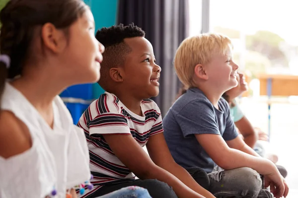 授業を聞きながら床に座る小学生のグループ — ストック写真