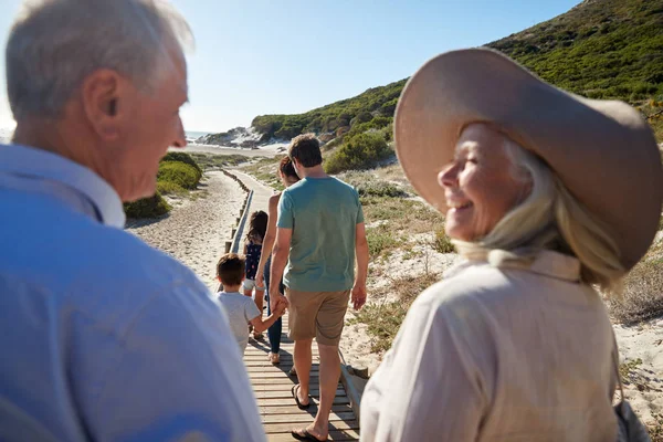 三代白人家庭走在沙滩上 祖父母在前景 在肩膀上的看法 — 图库照片