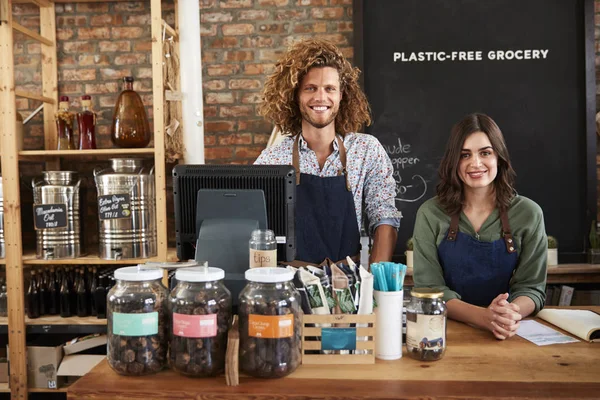 セールスデスクの背後にある持続可能なプラスチックフリー食料品店の男性と女性の所有者の肖像 — ストック写真