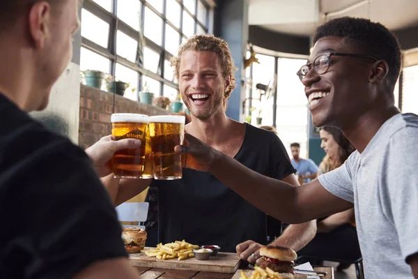 Tres jóvenes amigos masculinos reunión para bebidas y alimentos haciendo un a — Foto de Stock