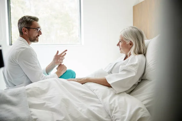 Doktor Beyaz Ceket Giyen Hastane Yatağında Olgun Kadın Hasta Ziyaret — Stok fotoğraf
