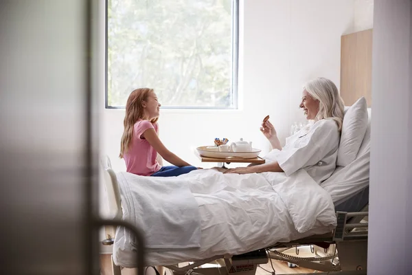 Barnbarn Som Besöker Mormor Sjukhussäng För Afternoon Tea — Stockfoto