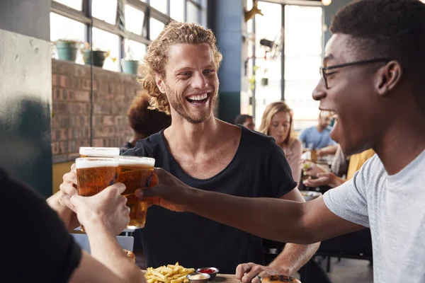 Tre unga manliga vänner möte för drinkar och mat gör en till — Stockfoto