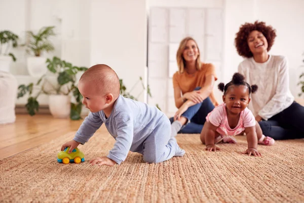 ロフトアパートの自宅で赤ちゃんと遊ぶ2人の母親の会合 — ストック写真