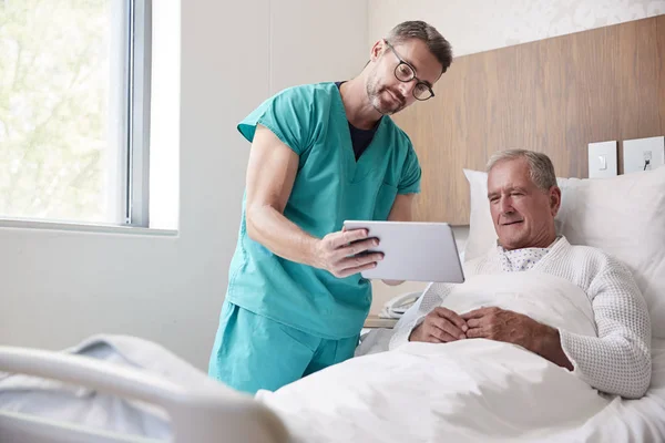 Dijital Tabletli Cerrah Geriatrik Ünitesinde Hastane Yatağında Kıdemli Erkek Hastayı — Stok fotoğraf