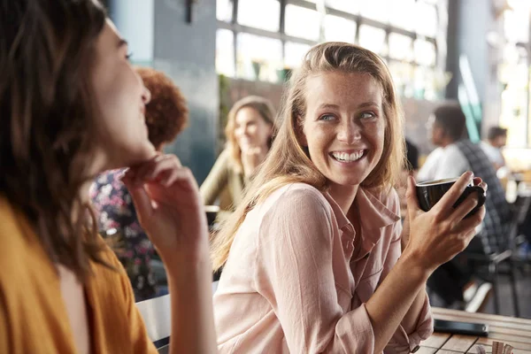 Duas amigas sentadas à mesa na cafetaria conversando — Fotografia de Stock