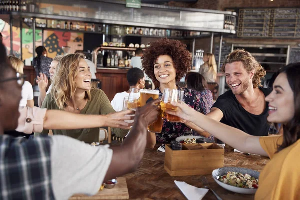 Grupo de jóvenes amigos reunión para bebidas y alimentos haciendo un Toas —  Fotos de Stock