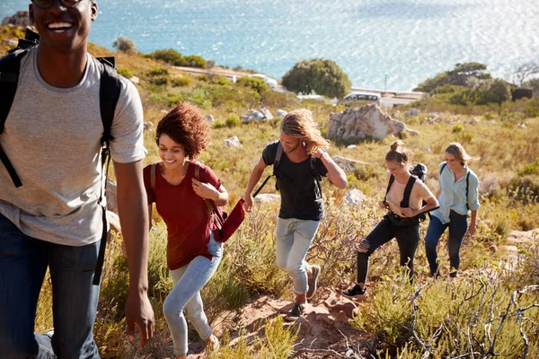 Jóvenes Amigos Adultos Senderismo Sola Fila Cuesta Arriba Camino Por Fotos de stock