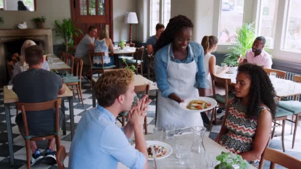 Junges Paar Wird Von Kellnerin Belebtem Restaurant Mit Essen Versorgt — Stockvideo