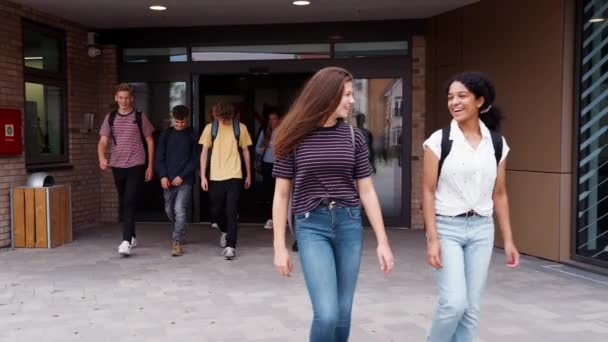 同級生と一緒に校舎を出る女子高校生2人の正面図 ゆっくりと撮影した動画 — ストック動画