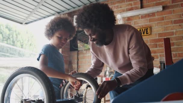 中年黑人父亲和十几岁的儿子站在工作台上 一起在车库里一起建造一辆赛车卡丁车 — 图库视频影像