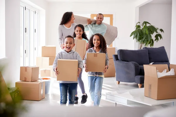笑顔の家族が引っ越しの日に新しい家に箱を運ぶ — ストック写真