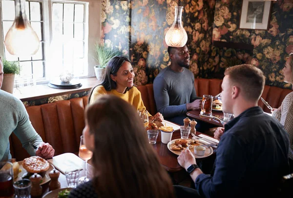 忙しい伝統的な英語のパブのレストランで食べる人々のグループ — ストック写真
