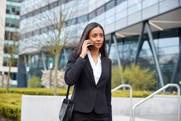 現代のオフィスビルの外で携帯電話で話す仕事に通うビジネスウーマン — ストック写真