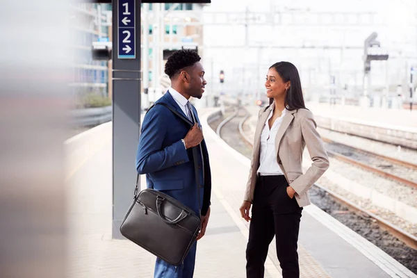 電車を待つ鉄道のプラットホームで話す仕事に通勤するビジネスマンとビジネスウーマン — ストック写真