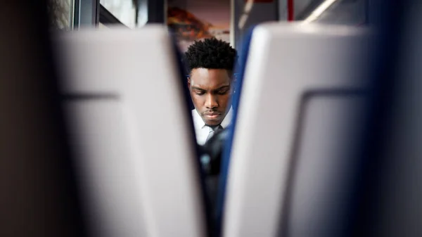 電車の中に座っているビジネスマンが2つの席の間を見て仕事に行く — ストック写真