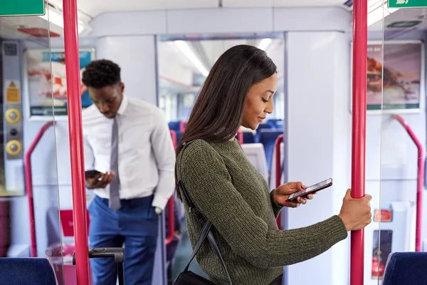 電車通勤中に立って携帯電話を見て通勤するビジネス客 — ストック写真