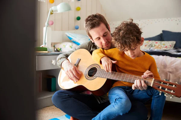 单亲父亲在家里与儿子教他在卧室演奏原声吉他 — 图库照片